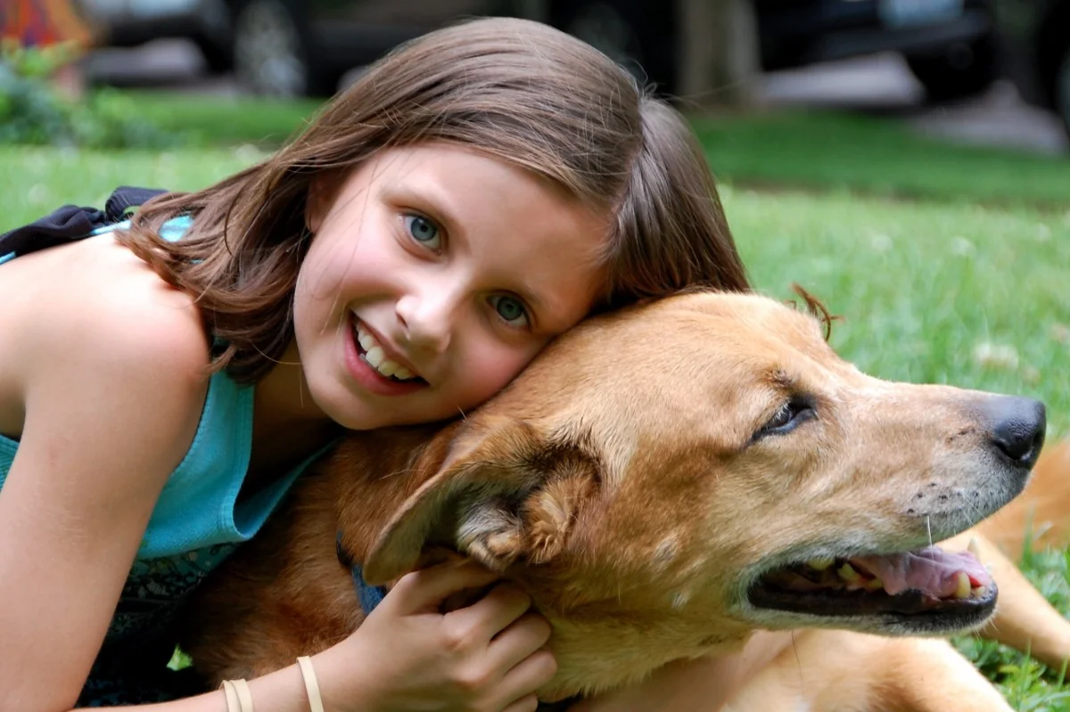 A girl smiles while embracing a golden retriever